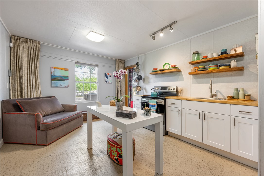 Kitchen has concrete flooring, electric stove, refrigerator, white cabinets, chopping block wood counter tops with track lighting. - If you have additional questions regarding 16301 E Lake Shore Drive  in Austin or would like to tour the property with us call 800-660-1022 and reference MLS# 7548762.