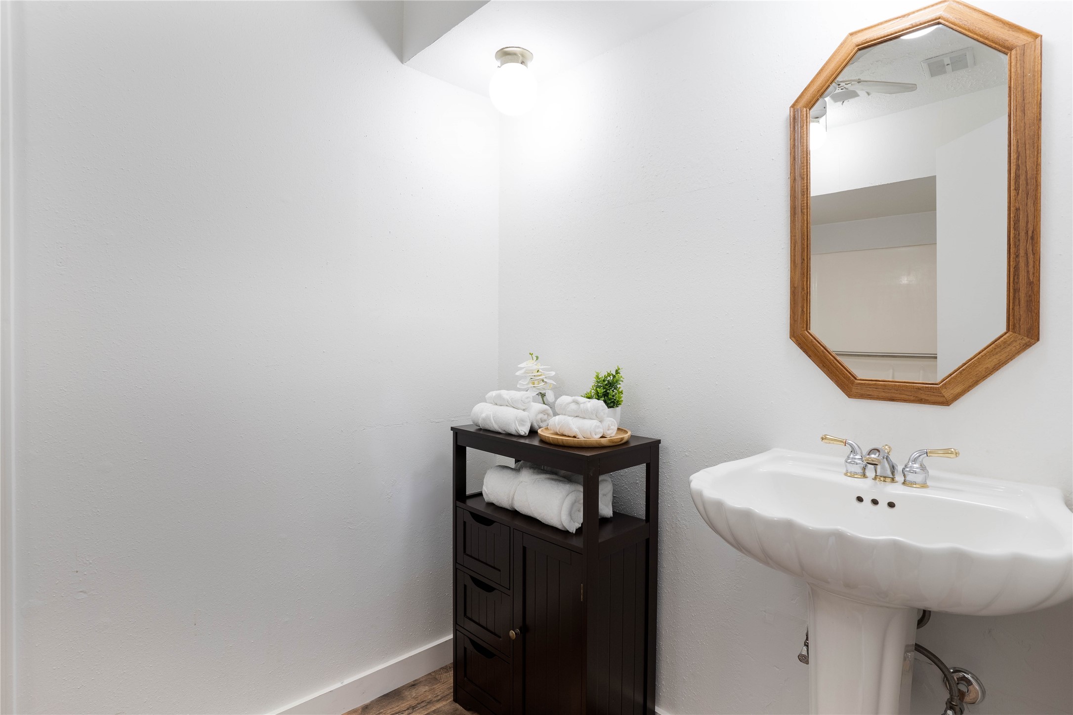 Large hall bath with a ceiling fan, pedestal sink, and single door floor cabinet. - If you have additional questions regarding 10218 Golden Sunshine Drive  in Houston or would like to tour the property with us call 800-660-1022 and reference MLS# 5796126.