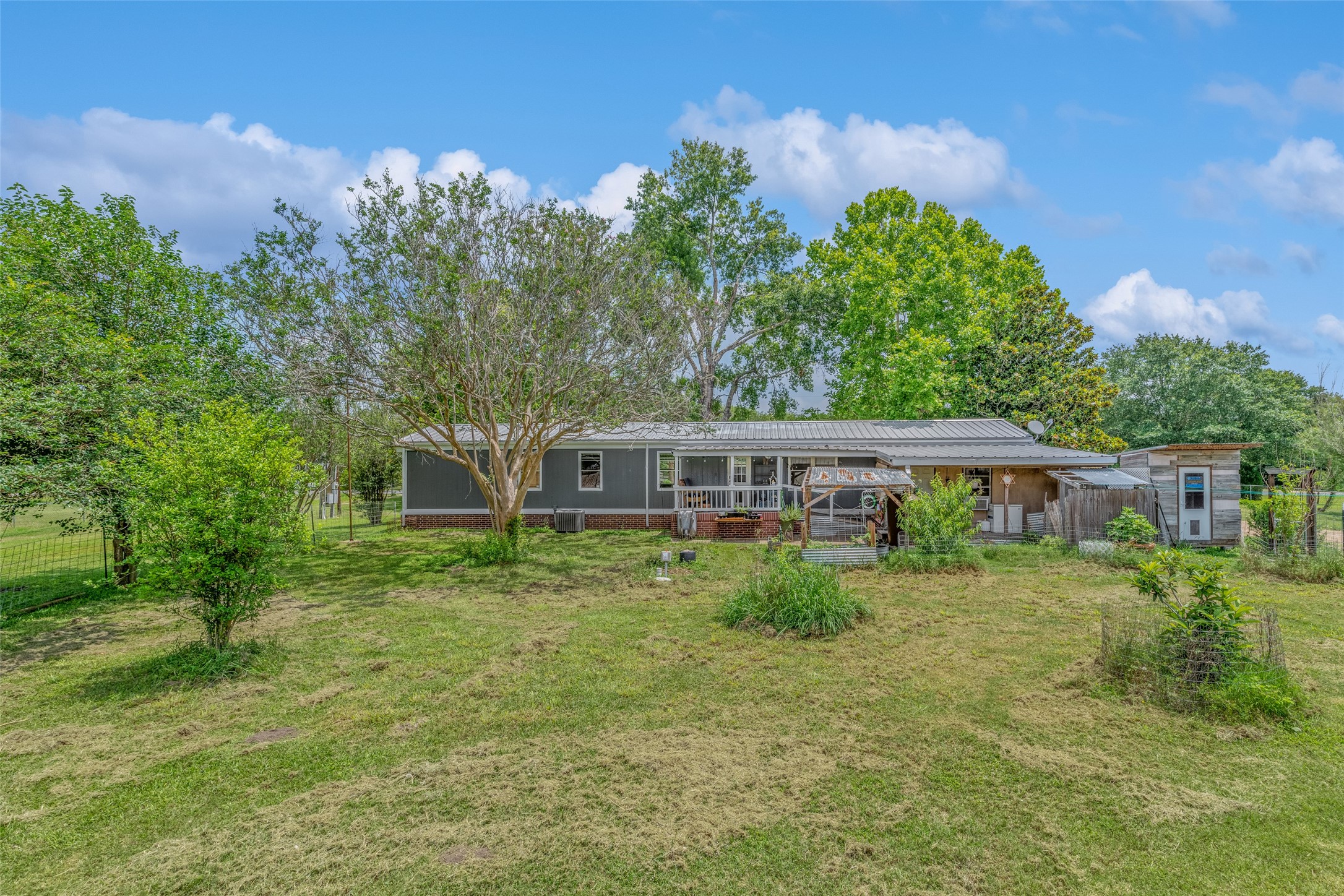 REAR OF MOBILE HOME FROM BACK YARD - If you have additional questions regarding 2055 Green Meadows Drive  in Sealy or would like to tour the property with us call 800-660-1022 and reference MLS# 16848431.